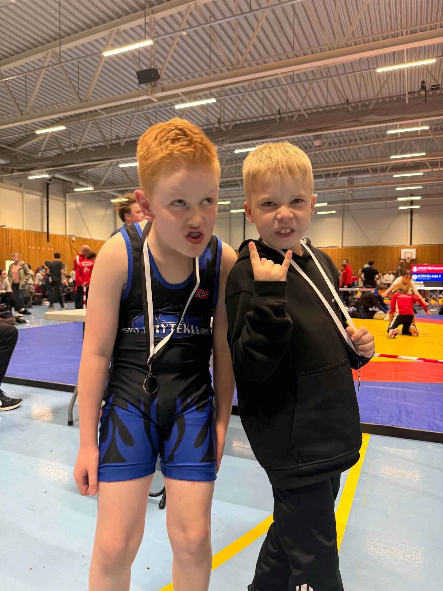 To unge Ski-brytere med medaljer og glimt i øyet i stevnehallen.