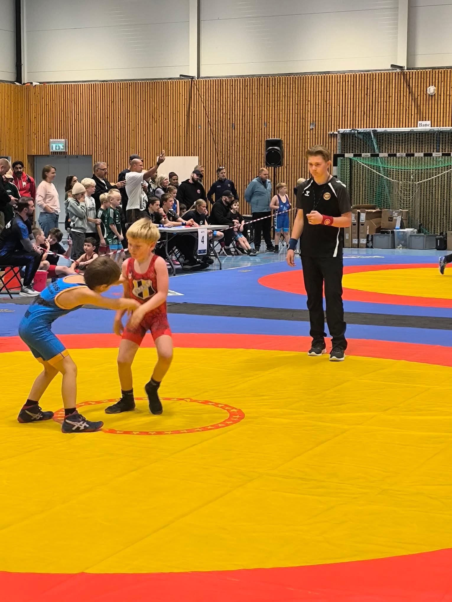 Marcus i dommerantrekk følger en kamp mellom to unge brytere under Skedsmo Cup.